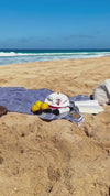Baseball cap hat snap back with 'The Merman' logo embroidered in red on a cream off white canvas on the beach