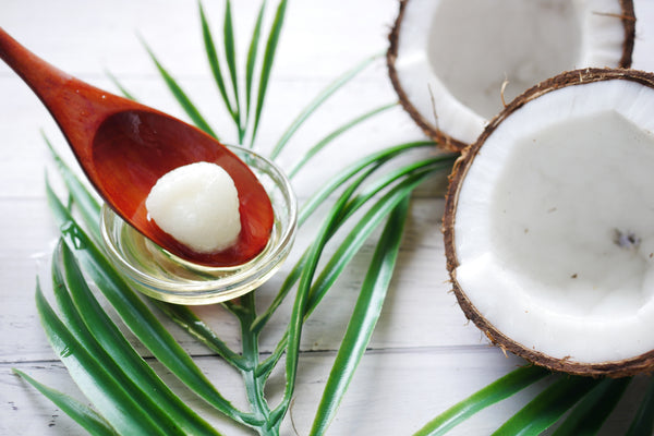 Spoonful of coconut oil next to a coconut